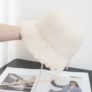 Close-up of beige crochet bucket hat with hollow knit texture and scalloped wavy brim