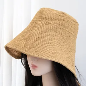 Close-up of a khaki woven straw hat with a wide brim showing fine texture on a model
