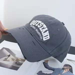 Detail of distressed brim and white 3D embroidery on a dark grey cotton baseball cap