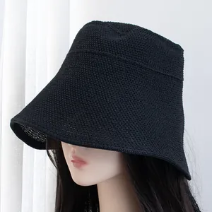 Close-up of the dense knit texture and wide brim of the black sun hat on a model
