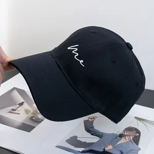 Close-up of white 'me' cursive embroidery on black cotton twill baseball cap