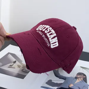 Close-up of distressed cotton baseball cap in burgundy with white embroidery details