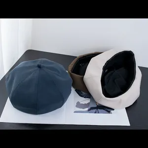 Bérets octogonaux rétro classiques en bleu marine, marron et beige sur un bureau minimaliste