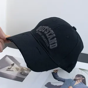Detail of distressed brim and embroidered OUTSTAND lettering on black cotton baseball cap