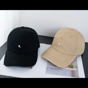 Detail der R-Stickerei auf schwarzen und beigen Baumwoll-Basecaps im 6-Panel-Design