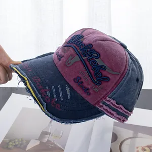 Detail of distressed denim baseball cap with BlackRebel embroidery and frayed edges