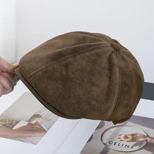 Dettaglio del berretto newsboy in finta pelle scamosciata marrone scuro con texture opaca