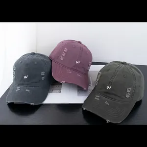Vue détaillée des casquettes vintage en coton délavé avec trous usés et broderie W élégante