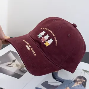 Close-up of cute rabbit embroidery and sports text on a burgundy cotton baseball cap