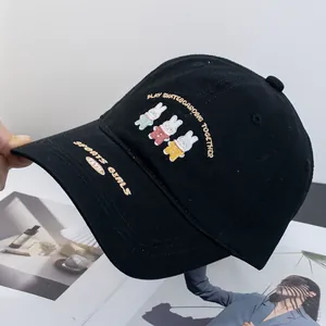 Close-up of cute rabbit embroidery and text on a black cotton baseball cap surface