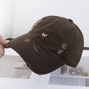 Gros plan sur la casquette marron vintage avec lettre W brodée rose et effet usé