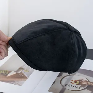 Dettaglio del berretto newsboy in camoscio nero con trama fine e cuciture eleganti