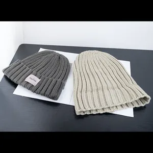 Minimalist knit beanie hats in dark grey and beige with vertical ribbed texture