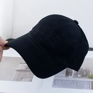 Detail of black cotton baseball cap with tonal embroidery on a minimalist magazine