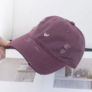 Gros plan d'une casquette violette vintage avec broderie W blanche et effet usé