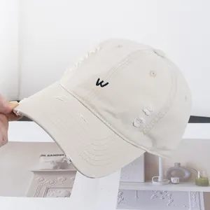 Détail de la casquette vintage avec broderie lettre W et bords effilochés usés