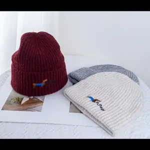 Détail de la broderie teckel sur divers bonnets en maille de différentes couleurs