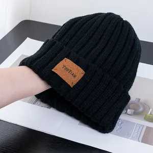 Close-up of black ribbed knit beanie featuring a brown vintage leather brand patch