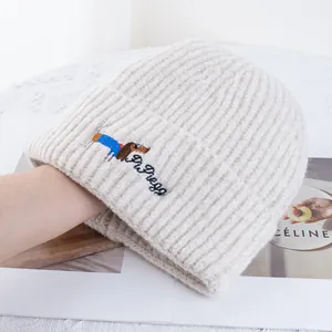 Gros plan du bonnet en tricot crème avec broderie de teckel et texture côtelée