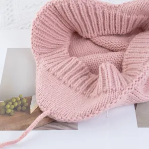 Rosa Strickmütze mit Ohrenklappen und Bindebändern für warme Wintermode im Vintage-Look