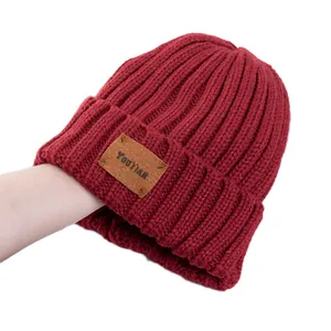 Deep red knit beanie with vintage leather patch and vertical rib texture for winter