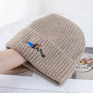 Détail de la broderie de teckel sur un bonnet en maille côtelée couleur avoine