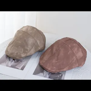Detail of khaki and pink PU leather berets featuring soft suede texture and fine stitching
