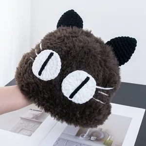 Dettaglio del berretto marrone a forma di gatto in peluche con grandi occhi lavorati