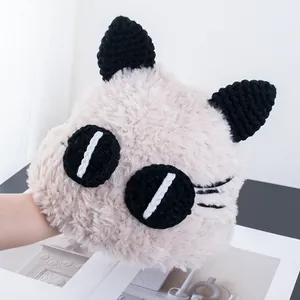 Dettaglio di peluche beige con occhi e orecchie di gatto lavorati a mano all'uncinetto