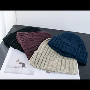 Dettaglio di quattro berretti in maglia a coste in nero, bordeaux, beige e blu navy