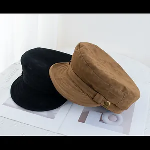 Detail of suede newsboy caps in black and brown with decorative gold metal buttons