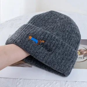 Détail de la broderie teckel sur un bonnet en maille côtelée gris foncé en laine douce