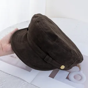 Detail of dark brown faux suede baker boy hat with a decorative gold metal button
