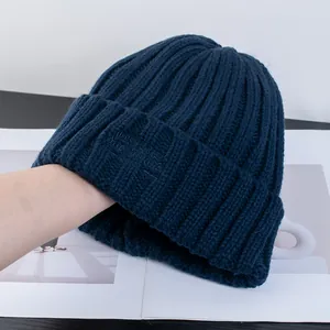 Dettaglio del berretto in maglia a coste blu navy con ricamo tono su tono