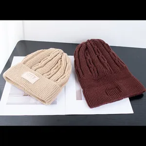 Detail van grof gebreide wintermutsen met CITY lederen patch in beige en bruin