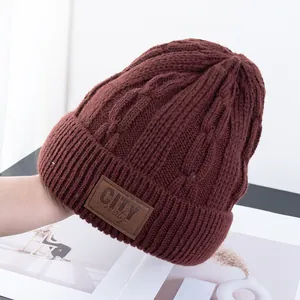 Detailopname van donkerrode gebreide muts met leren patch en omgeslagen rand