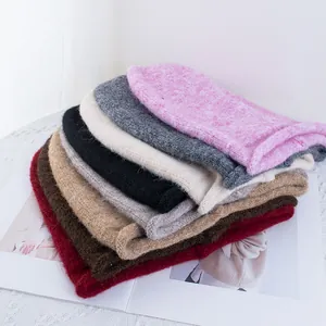 Berretti in maglia peluche in vari colori impilati su sfondo di pizzo bianco