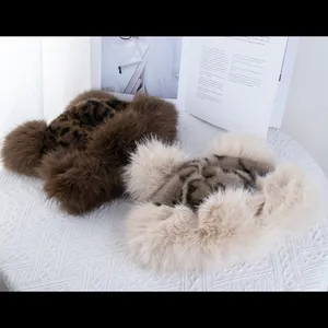 Close-up of leopard print faux fur winter hats in brown and beige on a textured surface