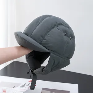 Close-up of dark grey quilted trapper hat with ear flaps and adjustable chin strap