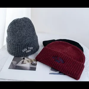 Detail of wool knit beanies with New York 1986 embroidery in grey, burgundy and black