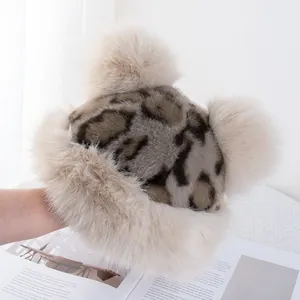 Detail of leopard print faux fur hat featuring soft texture and dual fluffy pom-poms
