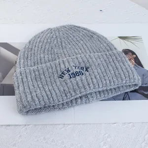 Close-up of gray wool knit beanie with New York 1986 embroidery detail and ribbed texture