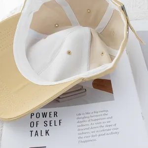 Interior view of beige cotton baseball cap showing sweatband and adjustable metal buckle