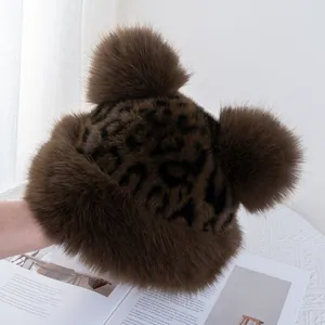 Close-up of leopard print faux fur winter hat with large pompoms and plush ear flaps