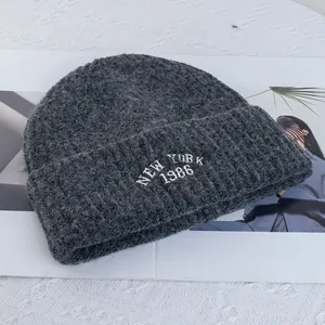 Detail of dark grey wool knit beanie featuring New York 1986 white embroidery