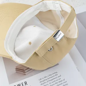 Detail of 100% cotton beige baseball cap showing adjustable metal buckle and inner stitching