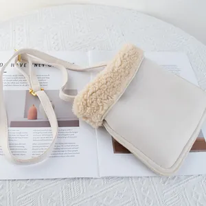 Detail of a creamy fleece shoulder bag with gold hardware on a stylish magazine background