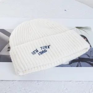 Detail view of cream knit beanie featuring navy New York 1986 embroidery on ribbed cuff