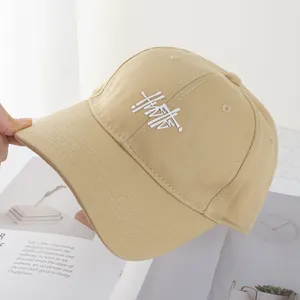 Detailed close-up of khaki baseball cap with 3D white embroidered HMTF logo and stitching