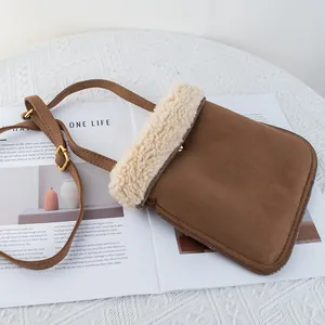 Detail of brown faux suede crossbody bag with soft white fleece trim and gold buckle